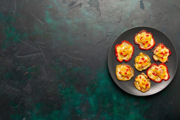 Top view cooked bell-peppers for lunch inside plate on the dark surface