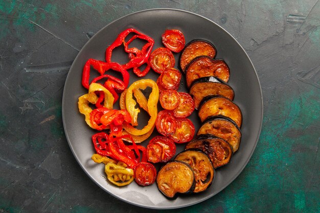 Top view cooked bell-peppers with eggplants on dark-green surface