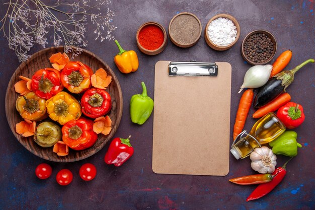 Top view cooked bell-peppers with fresh vegetables and seasonings on dark grey surface meal dolma vegetables beef meat