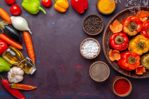 Top view cooked bell-peppers with fresh vegetables and seasonings on a grey surface meal dolma food vegetable beef meat