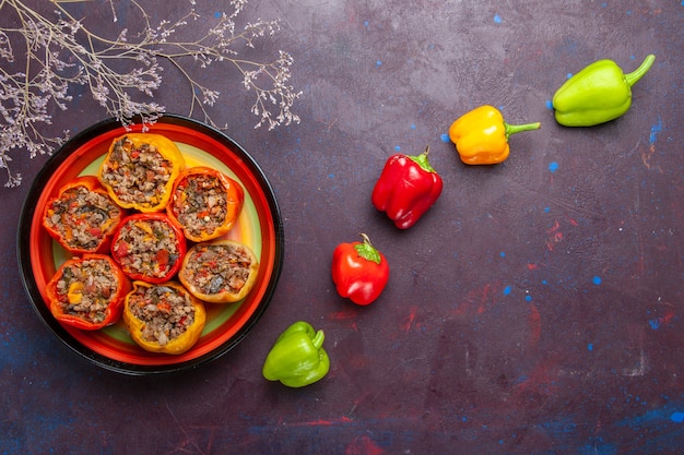 Foto gratuita vista dall'alto peperoni cotti con carne macinata su una scrivania grigia pasto dolma manzo cibo verdure carne