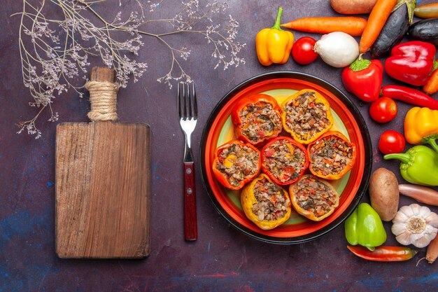 Top view cooked bell-peppers with vegetables and different seasonings on dark grey surface food dolma vegetable meal beef