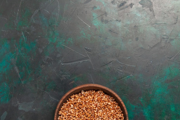 Top view cooked buckwheat tasty meal inside brown plate on dark-green surface