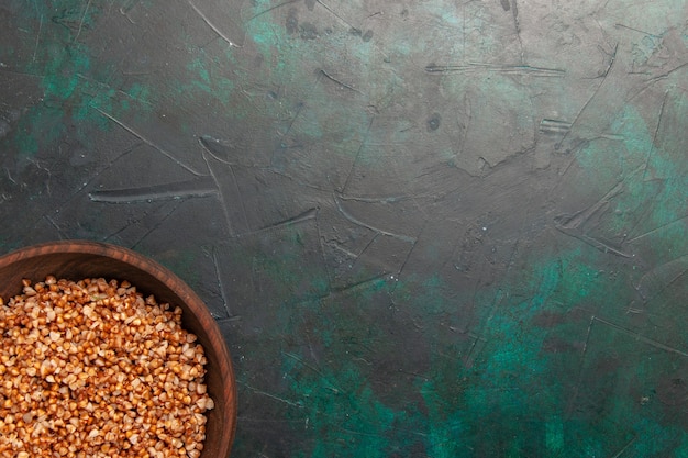 Vista dall'alto pasto gustoso di grano saraceno cucinato all'interno del piatto marrone sulla superficie verde scuro