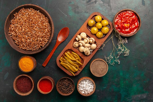 Top view cooked buckwheat with different seasonings on dark-green surface