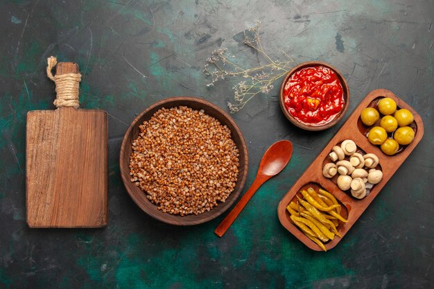 Top view cooked buckwheat with tomato sauce on the dark green surface