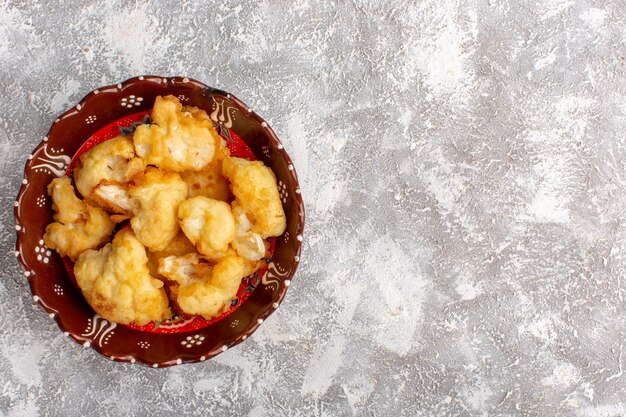 Top view of cooked cauliflower inside plate on white-light surface