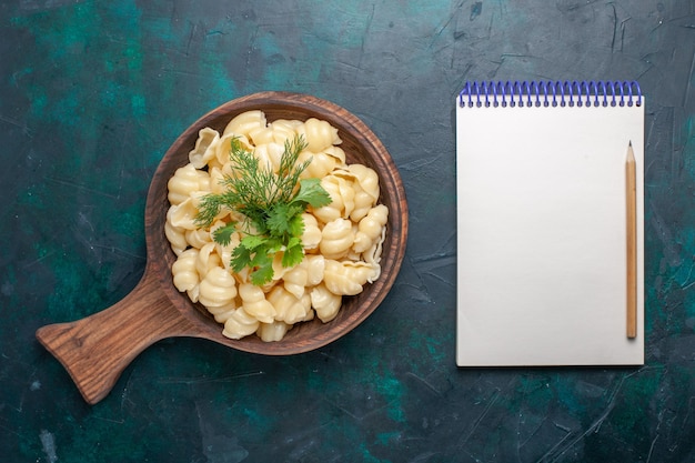 Free photo top view cooked dough pasta with greens and notepad on the dark surface
