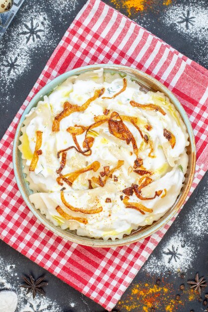 Top view cooked dough pieces with fried onions and different ingredients on dark surface