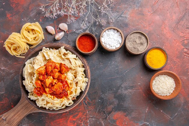 Top view cooked dough with chicken and sauce on dark desk dark pasta dough dish