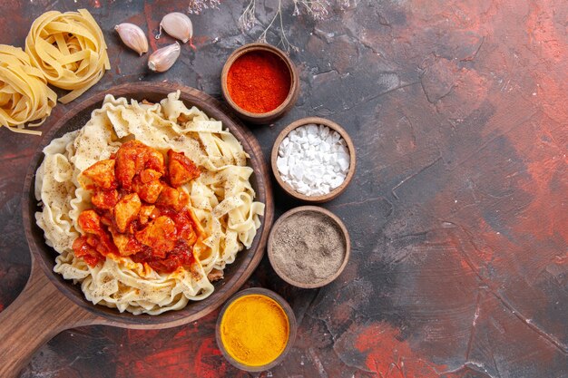 Top view cooked dough with chicken and sauce on the dark surface dark pasta dough dish