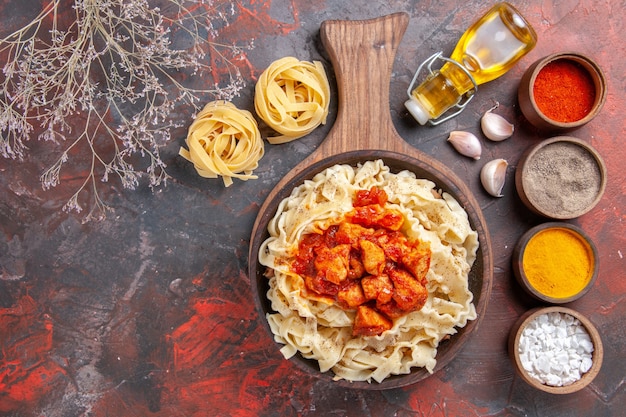 Top view cooked dough with chicken and seasonings on dark desk dough dark pasta dish