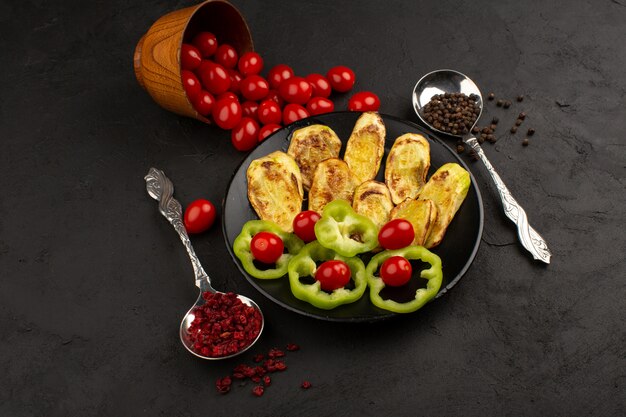 top view cooked eggplant along with sliced green bell pepper and whole red tomatoes on the dark desk