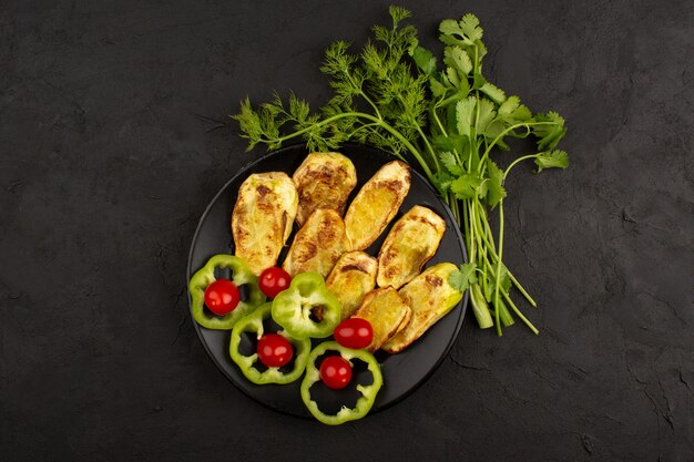 top view cooked eggplant inside black plate along with sliced green bell pepper and red cherry tomatoes on the dark