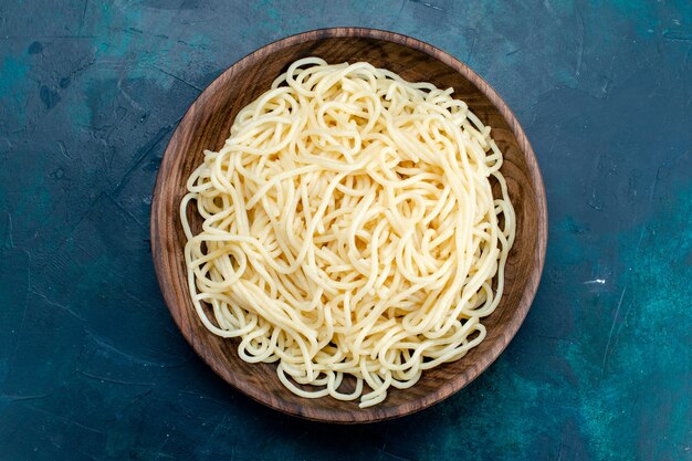 Top view cooked italian pasta inside round wooden plate on blue background pasta italy food dinner dough meat