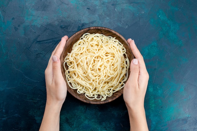 Top view cooked italian pasta inside round wooden plate on the blue background pasta italy food dinner dough meat