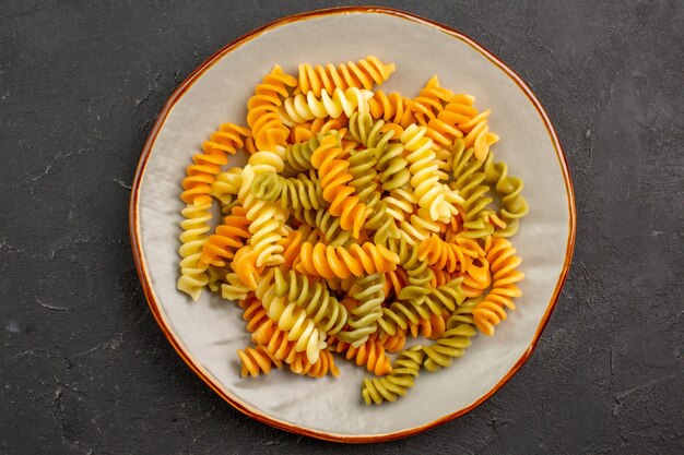 Top view cooked italian pasta unusual spiral pasta inside plate on dark space