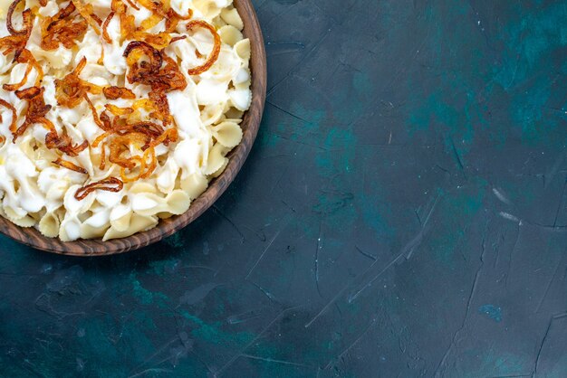 Top view cooked italian pasta with fried onions on blue desk