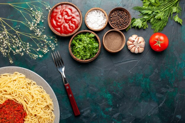 Top view cooked italian pasta with meat and different seasonings on the dark blue surface