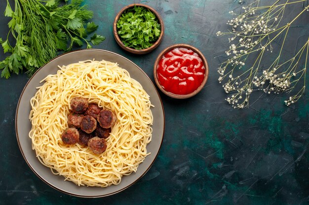진한 파란색 표면에 고기 토마토 소스와 채소로 만든 이탈리아 파스타 상위 뷰