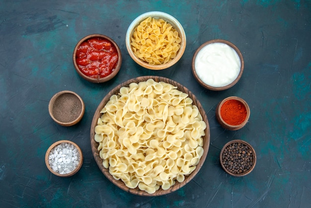 Top view cooked italian pasta with seasonings on dark