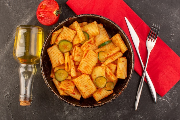 A top view cooked italian pasta with tomato sauce and cucumber inside pan