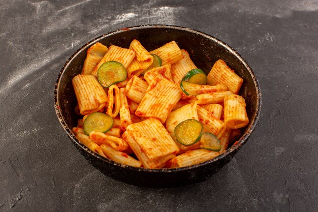 A top view cooked italian pasta with tomato sauce and cucumber inside pan