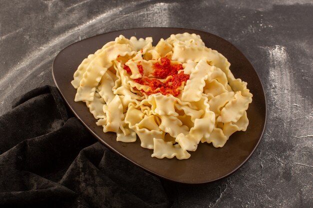 Вид сверху приготовленные итальянские макароны с томатным соусом внутри темной тарелки