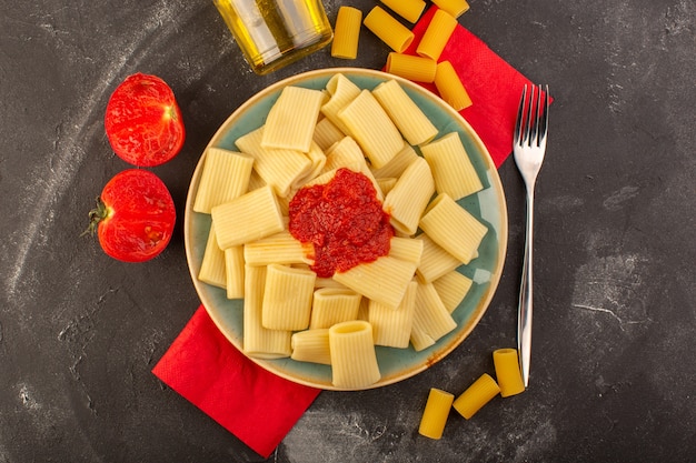 Вид сверху приготовленная итальянская паста с томатным соусом внутри тарелки с оливковым маслом