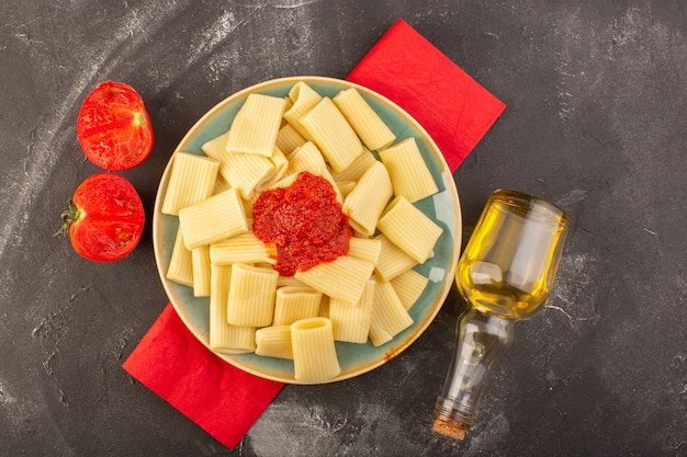 A top view cooked italian pasta with tomato sauce inside plate with olive oil