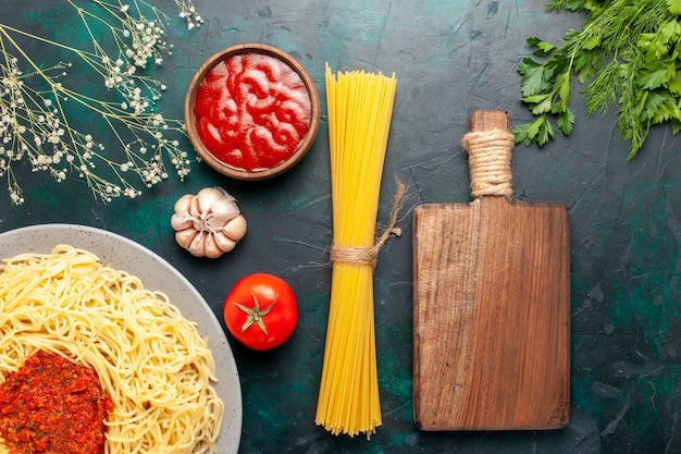 Вид сверху приготовленные итальянские макароны с фаршем в томатном соусе на синем столе