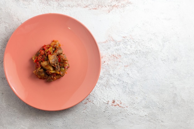 Top view cooked meat sliced and with vegetables inside plate on white surface