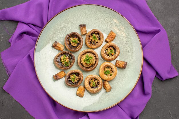 Free photo top view cooked mushrooms inside plate on purple tissue dish meal cooking mushrooms dinner