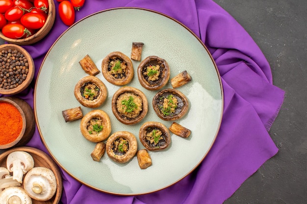 Vista dall'alto funghi cotti all'interno del piatto con condimenti sul piatto in tessuto viola che cucina la cena dei funghi