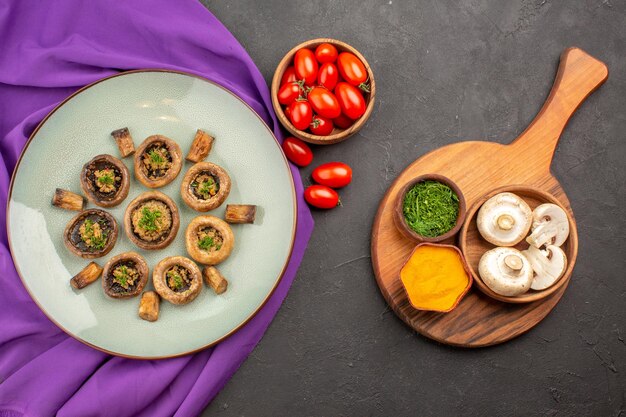 Top view cooked mushrooms inside plate with tomatoes and greens on dark surface dish mushrooms dinner cooking meal