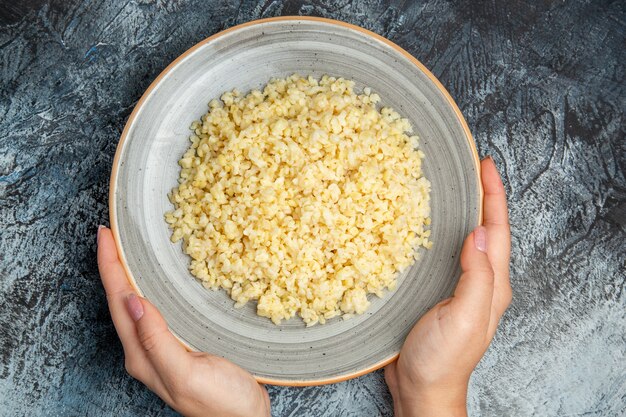 Top view of cooked pearl barley inside plate on dark surface