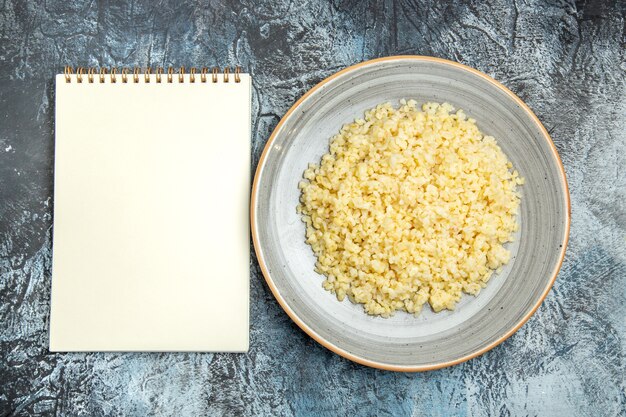 Top view of cooked pearl barley inside plate on light surface