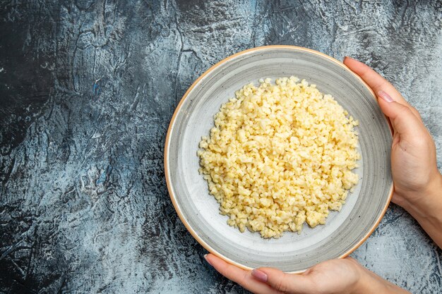 Top view of cooked pearl barley inside plate on light surface