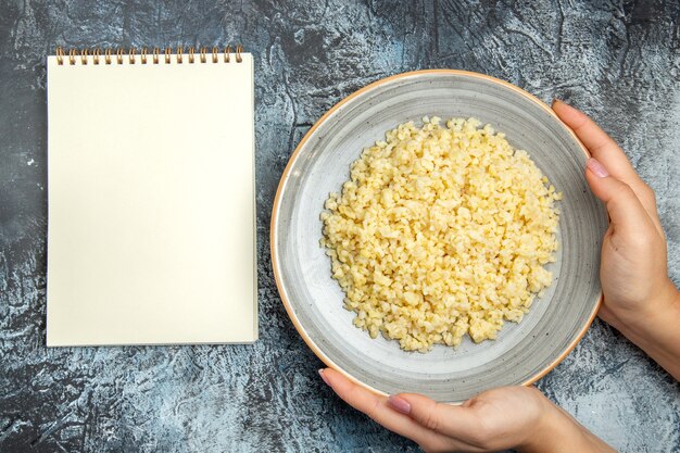 Top view of cooked pearl barley inside plate with notepad on light surface