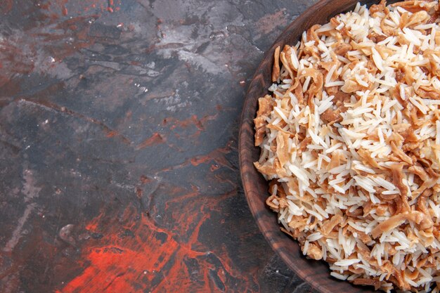 暗い表面の皿の食事の食糧パスタの生地のスライスが付いている上面図の炊飯米