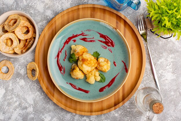 Top view of cooked sliced cauliflower inside blue plate on the white surface