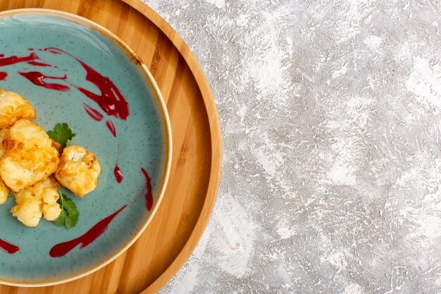 Top view of cooked sliced cauliflower inside plate on the white surface