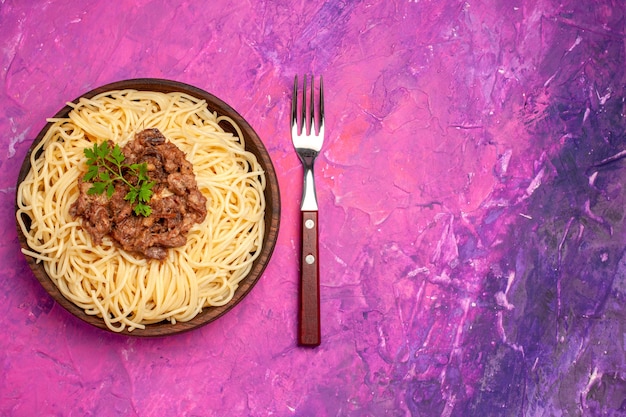 Top view cooked spaghetti with ground meat on light pink table color dish dough pasta