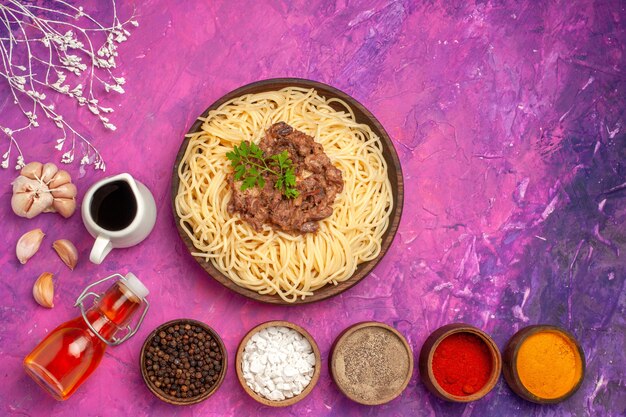 Top view cooked spaghetti with ground meat on pink table seasoning dough pasta dish