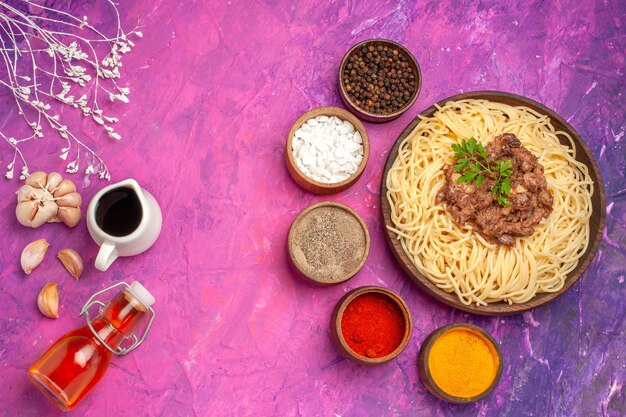 Top view cooked spaghetti with ground meat on pink table seasoning dough pasta