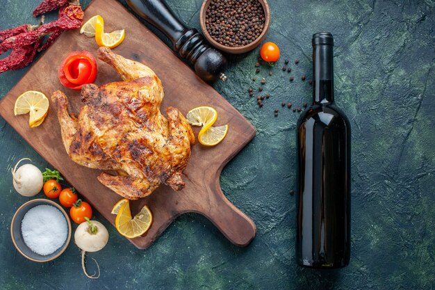 Top view cooked spiced chicken with bottle of wine on dark blue surface