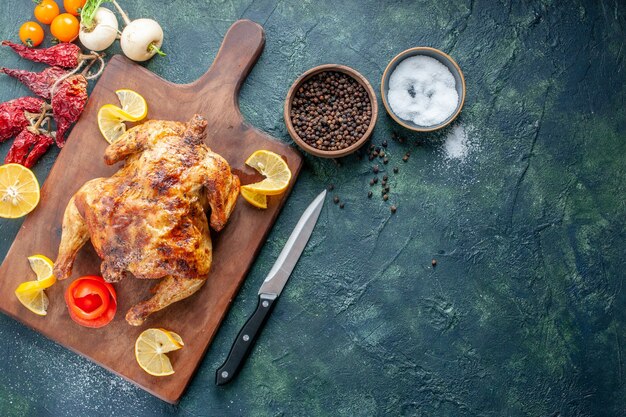 Top view cooked spiced chicken with lemon slices on dark surface