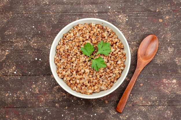 Top view cooked tasty buckwheat inside plate on dark