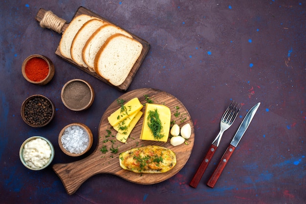 Free photo top view cooked tasty squashes with seasonings cheese and bread loafs on the dark-purple desk.