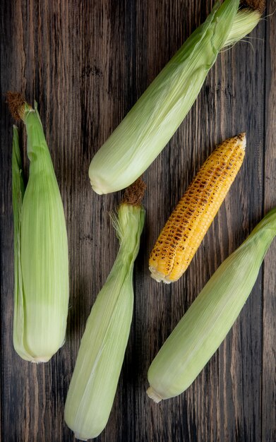 Top view of cooked and uncooked corns on wood 1